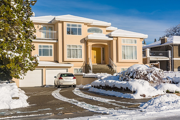 Residential house with front yard in snow and car on the driveway.